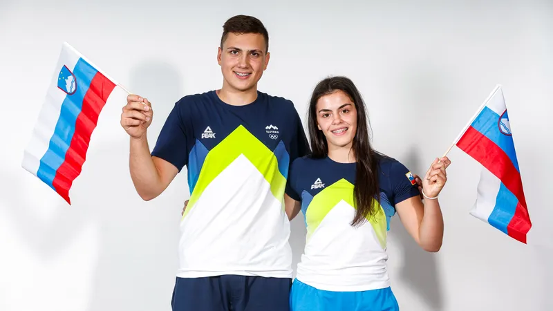 Moški in ženska v športnih majicah z logotipom Slovenije, vsak drži zastavo Slovenije.