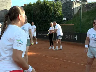 Skupina ljudi v belih majicah se igra z teniškimi žogicami na teniškem igrišču.